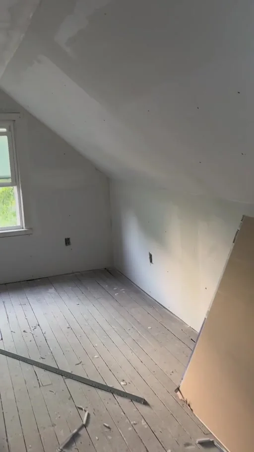Still from the project video showing installed drywall on the attic walls and sloped ceiling before final finishes.