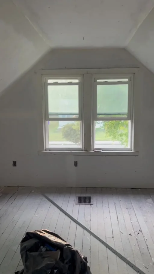 Still from the project video showing the attic window wall and ceiling after drywall installation, with finishing work ongoing.