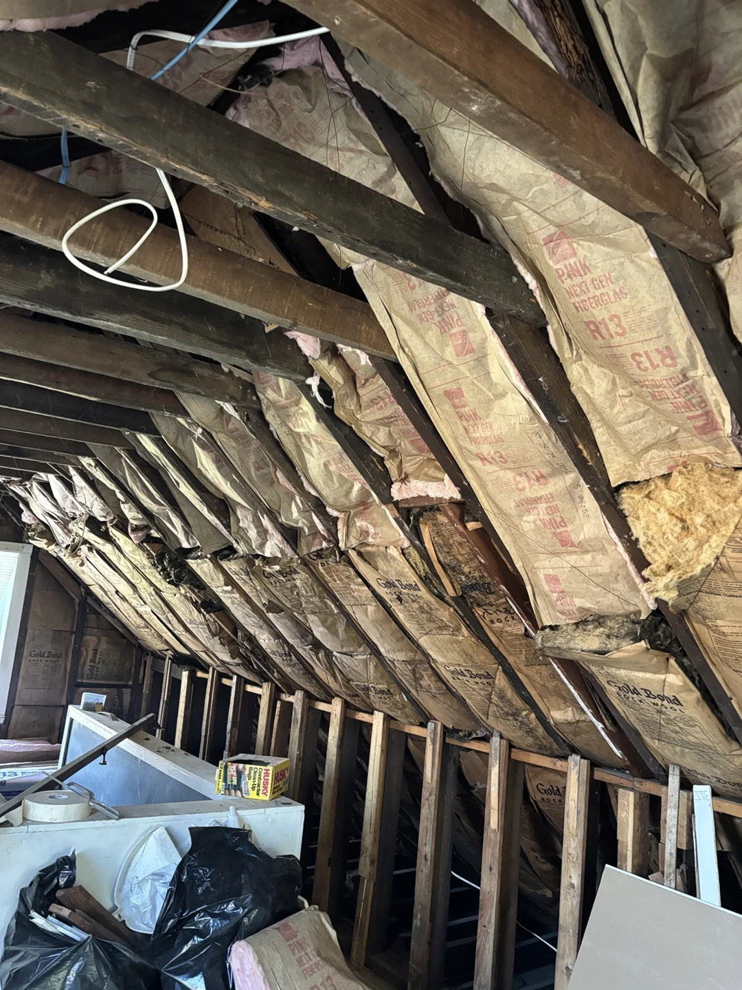 Attic renovation with exposed roof framing, insulation and wall studs.