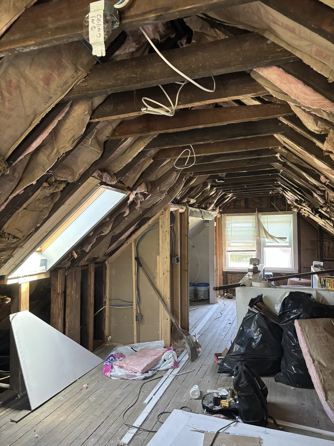 Attic room during renovation with a skylight, exposed framing and insulation.