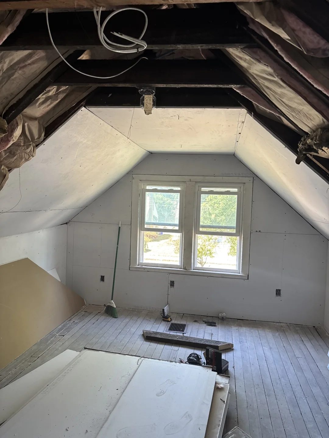 New drywall around the attic windows and lower sloped ceiling, with ceiling work in progress.