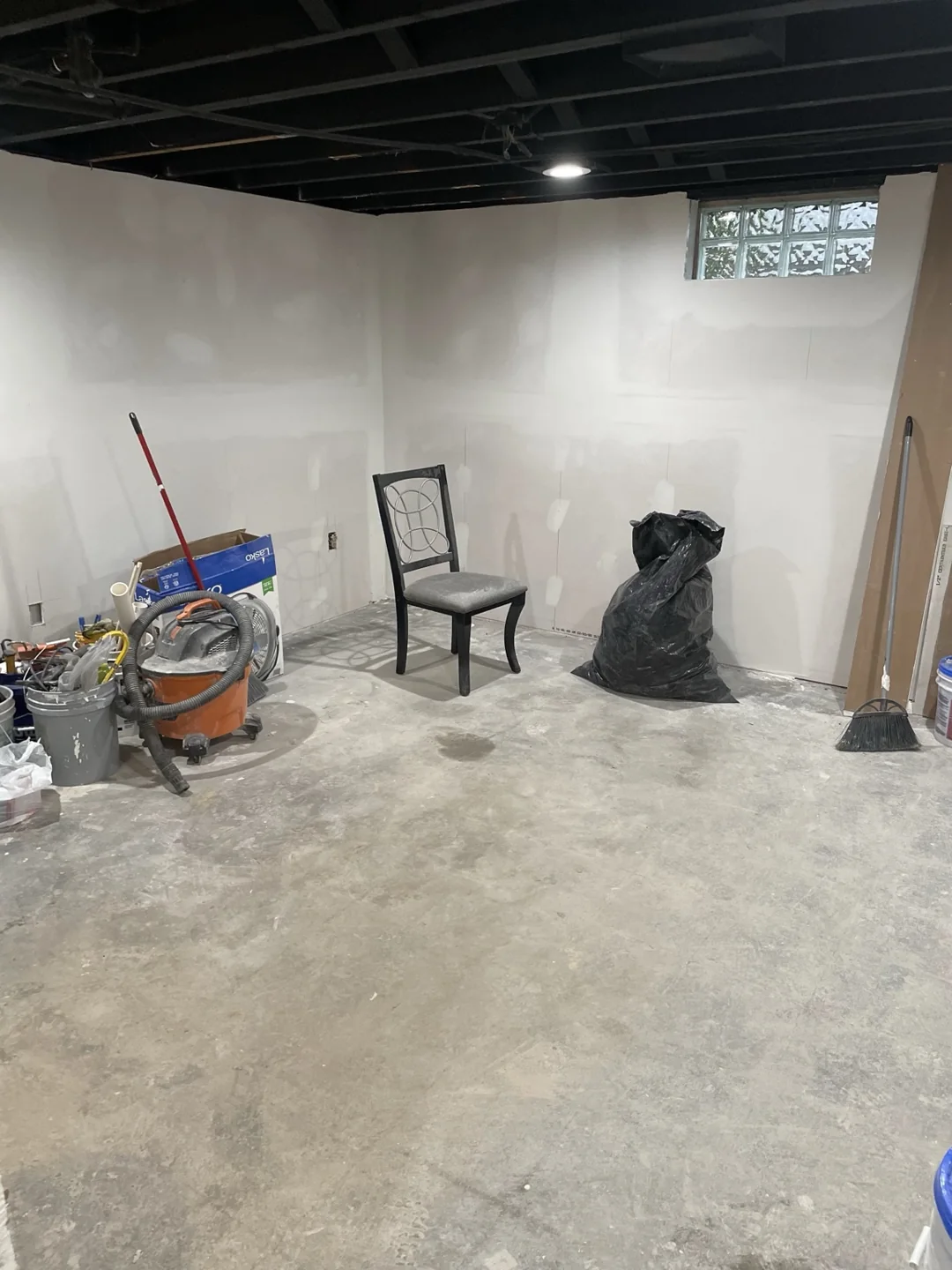 Another view of basement drywall progress beneath the exposed black ceiling.