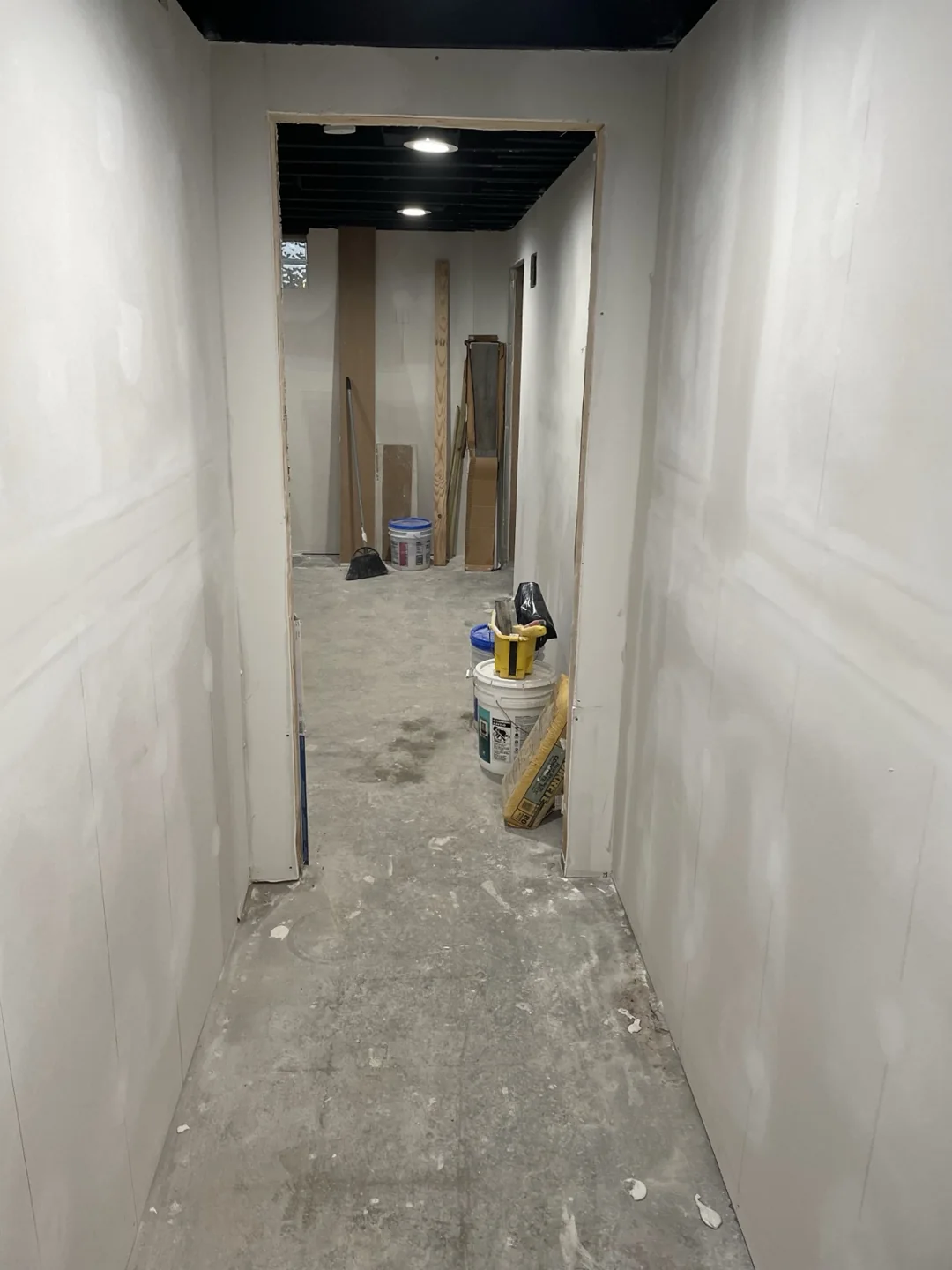 Basement hallway with drywall seams being finished before painting.