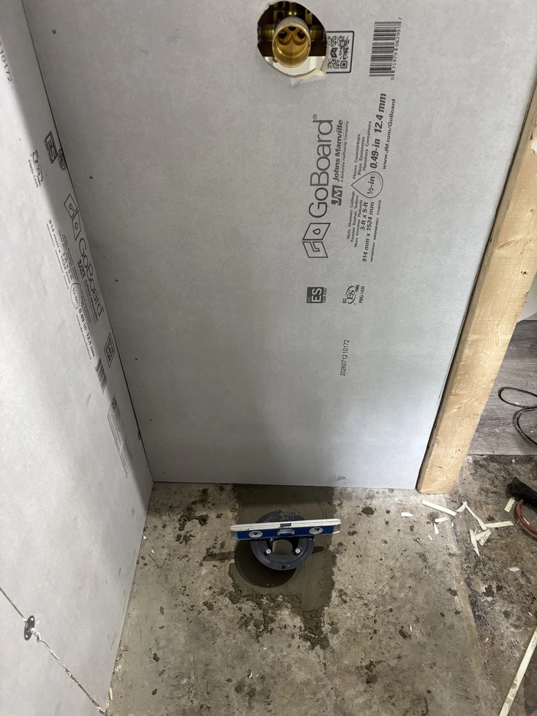 Bathroom renovation in progress with backer board installed and the floor being prepared around a plumbing opening.
