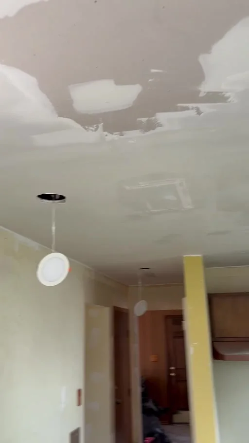 Video still showing ceiling joints and patches during smoothing, with LED fittings being installed.