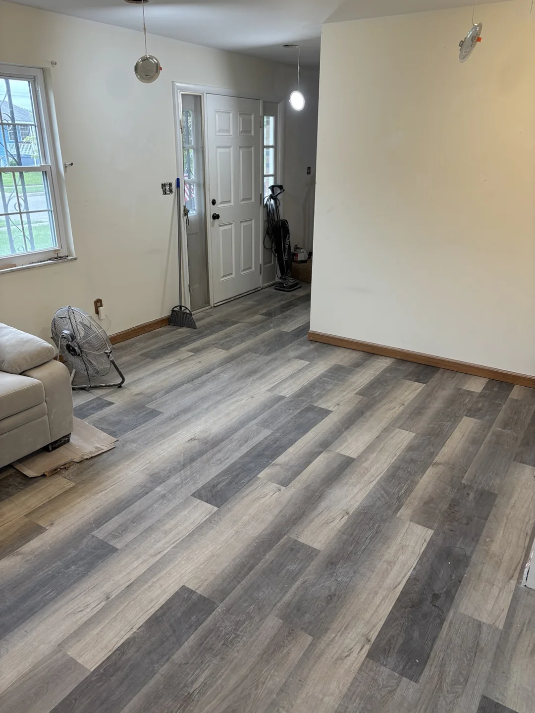 Installed gray wood-look plank flooring in the living area, with ceiling light fitting still underway.