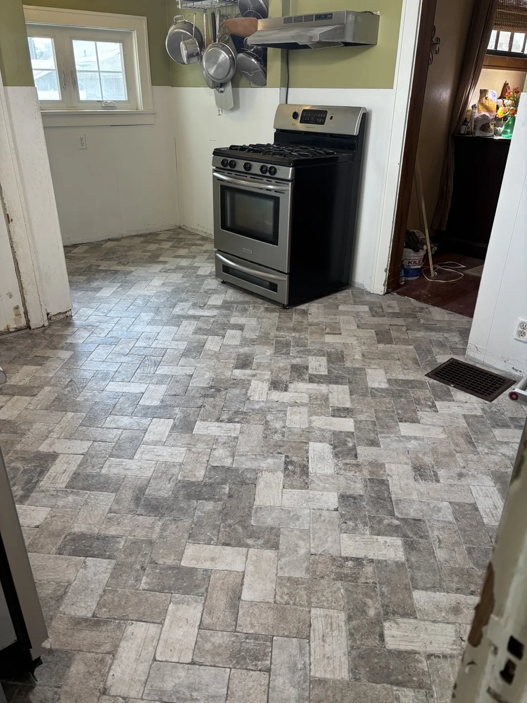 New gray and beige herringbone-pattern kitchen flooring around the range.