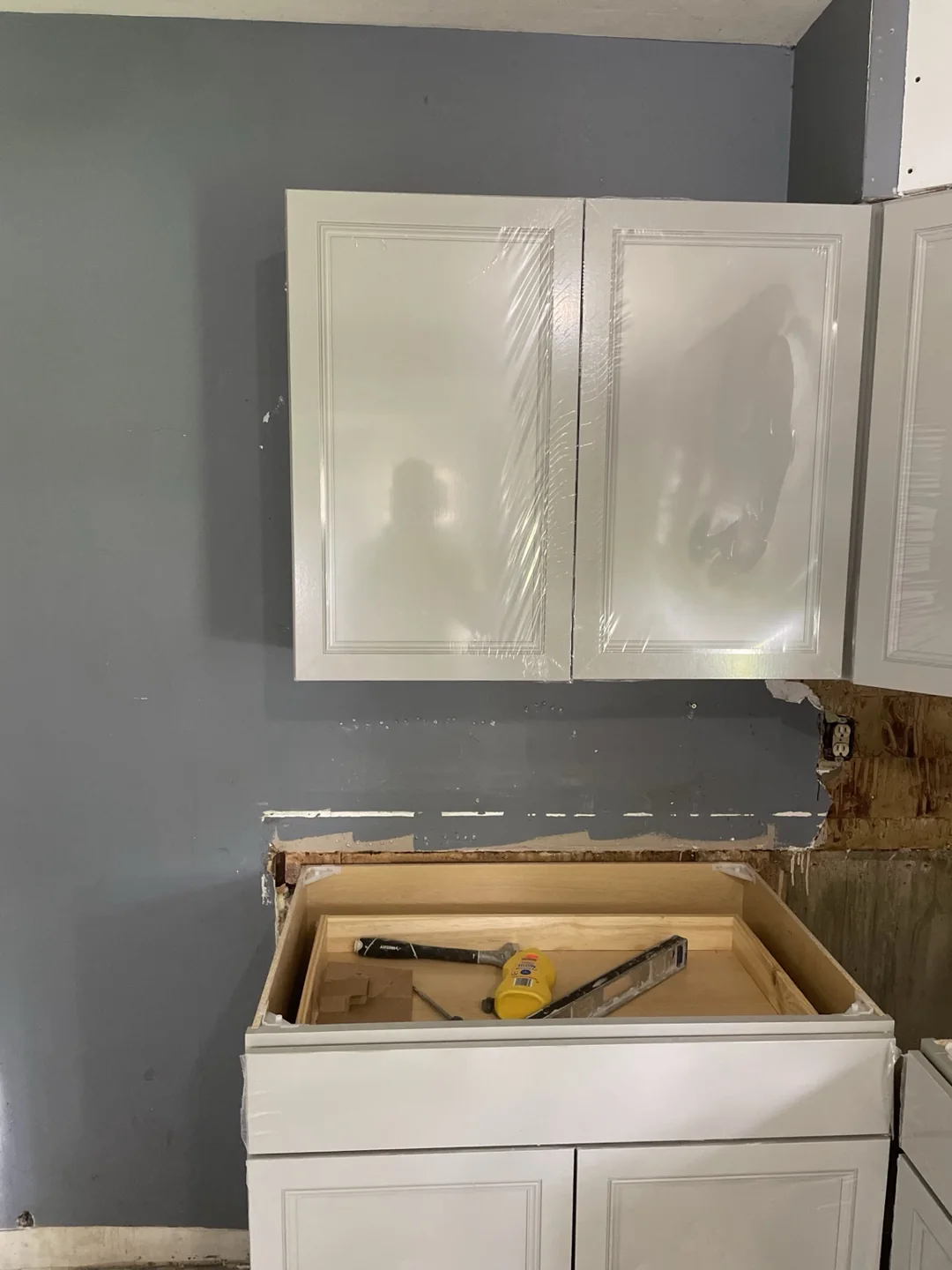 Close-up of gray kitchen cabinets with protective film during installation.