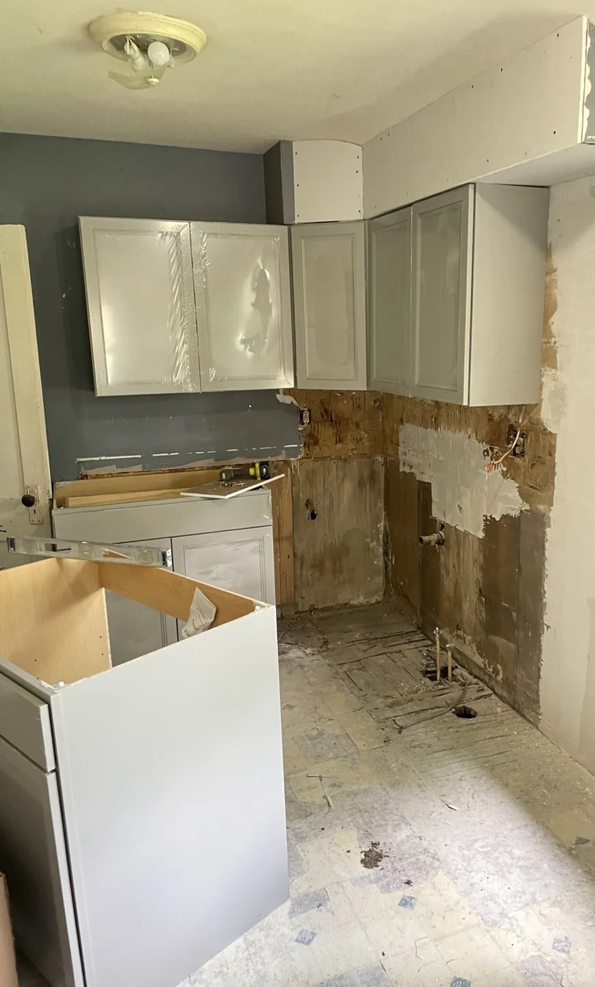 New gray upper cabinets and base cabinets being installed in the kitchen.