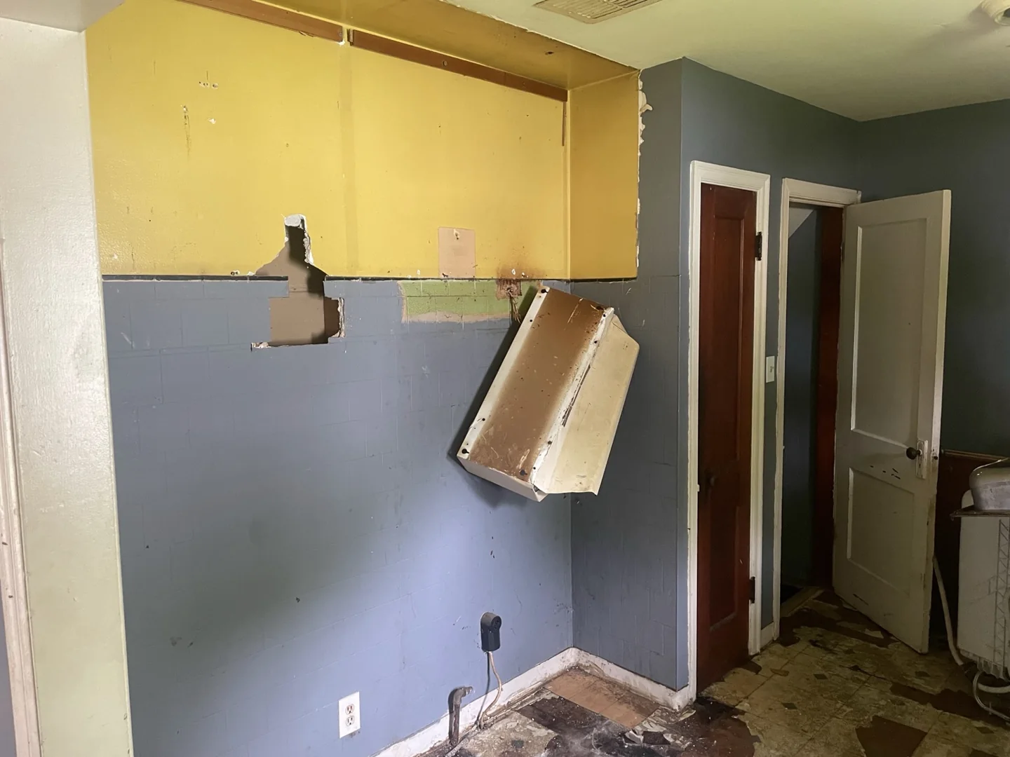 Kitchen wall after cabinet removal, with exposed wall areas and flooring.