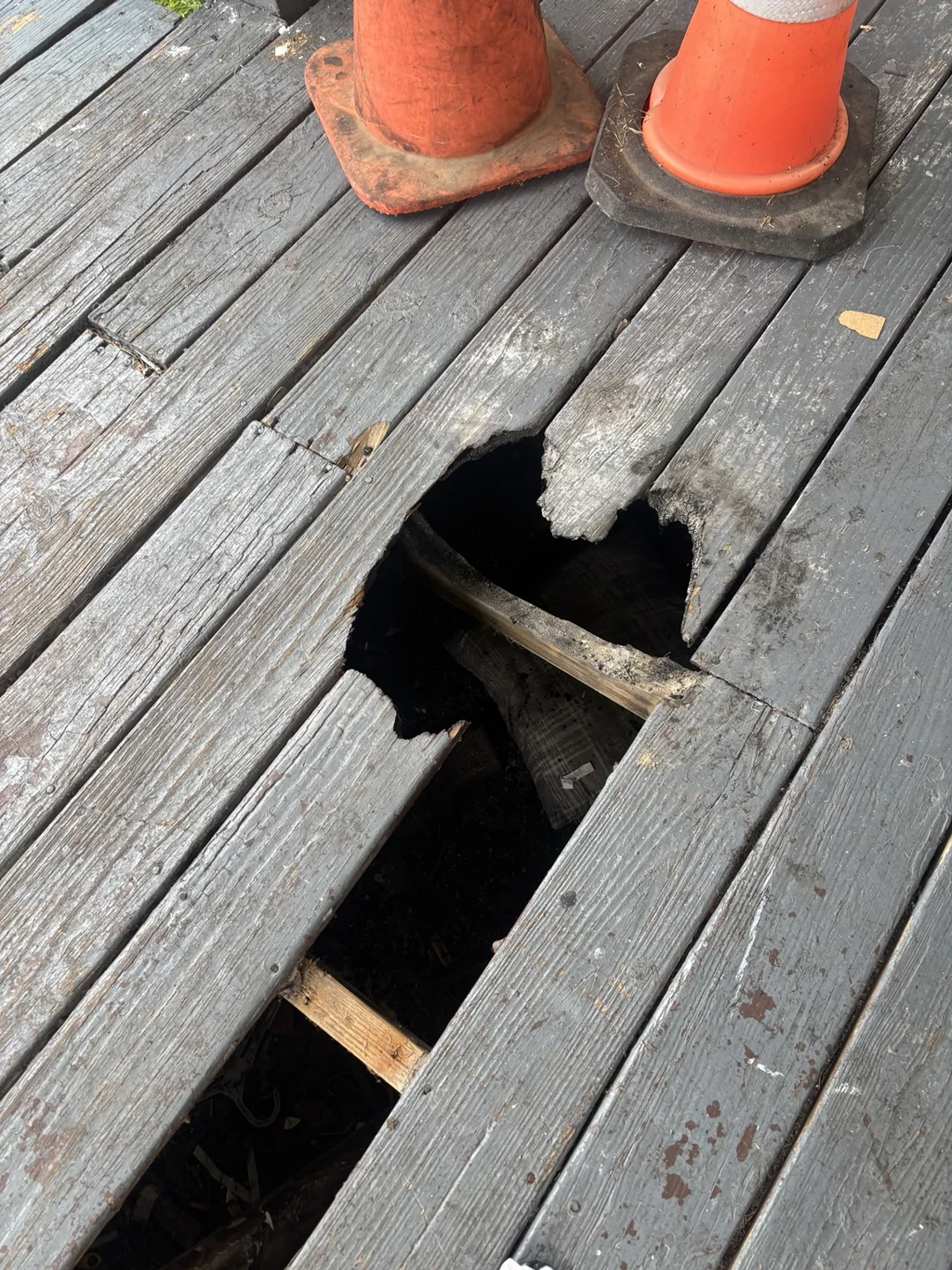 Close-up of broken porch boards and the framing beneath them.