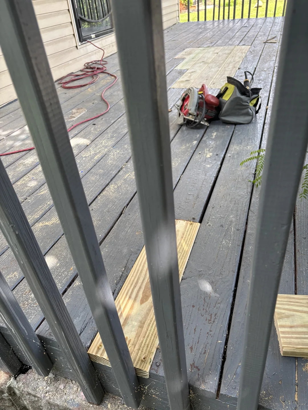 New wood boards installed alongside the existing painted porch decking.