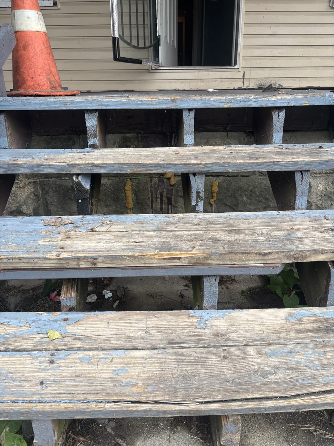 Close view of worn wooden porch stair treads before repairs.