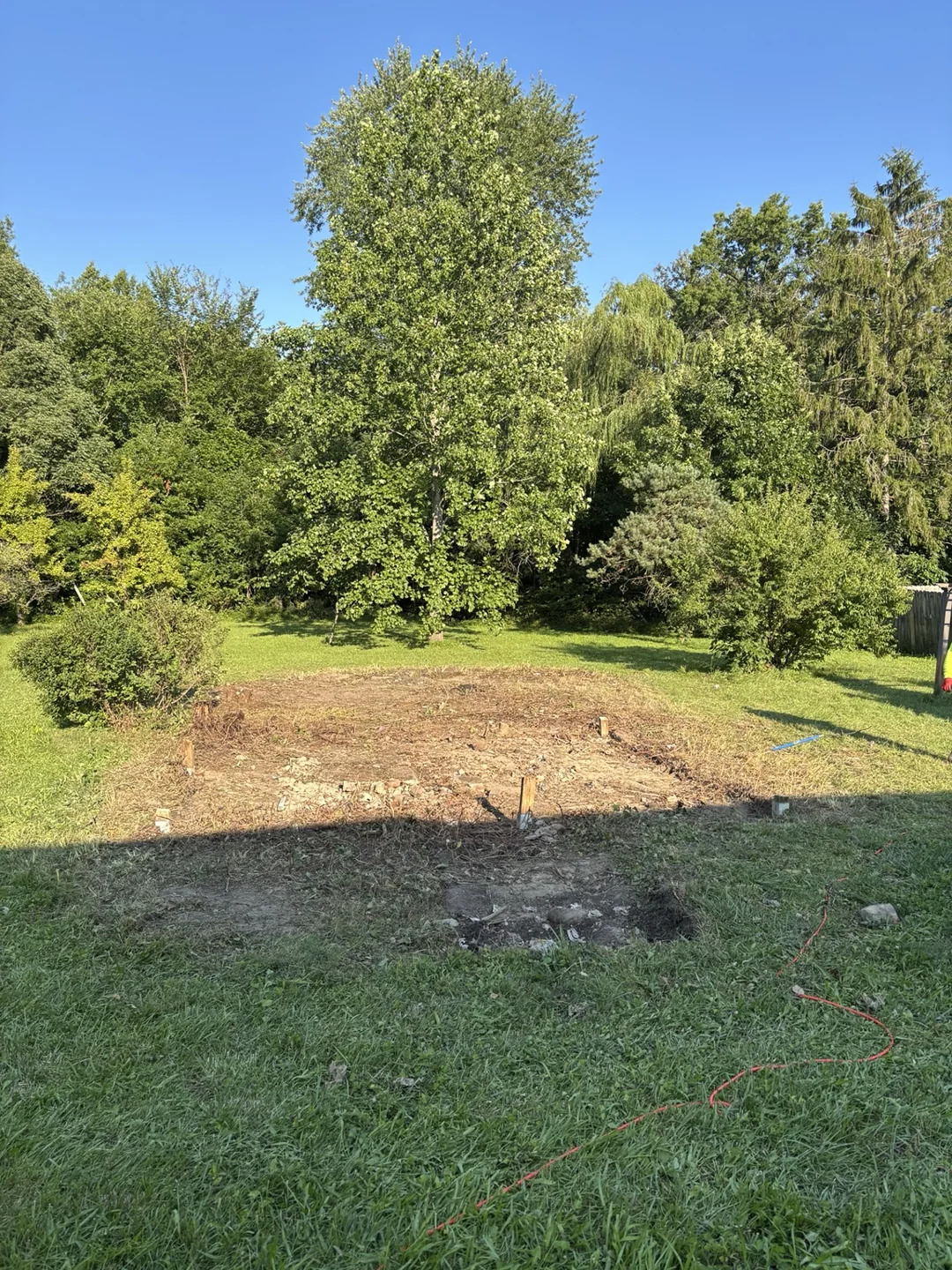 Wide view of the cleared shed area with exposed ground and surrounding lawn.
